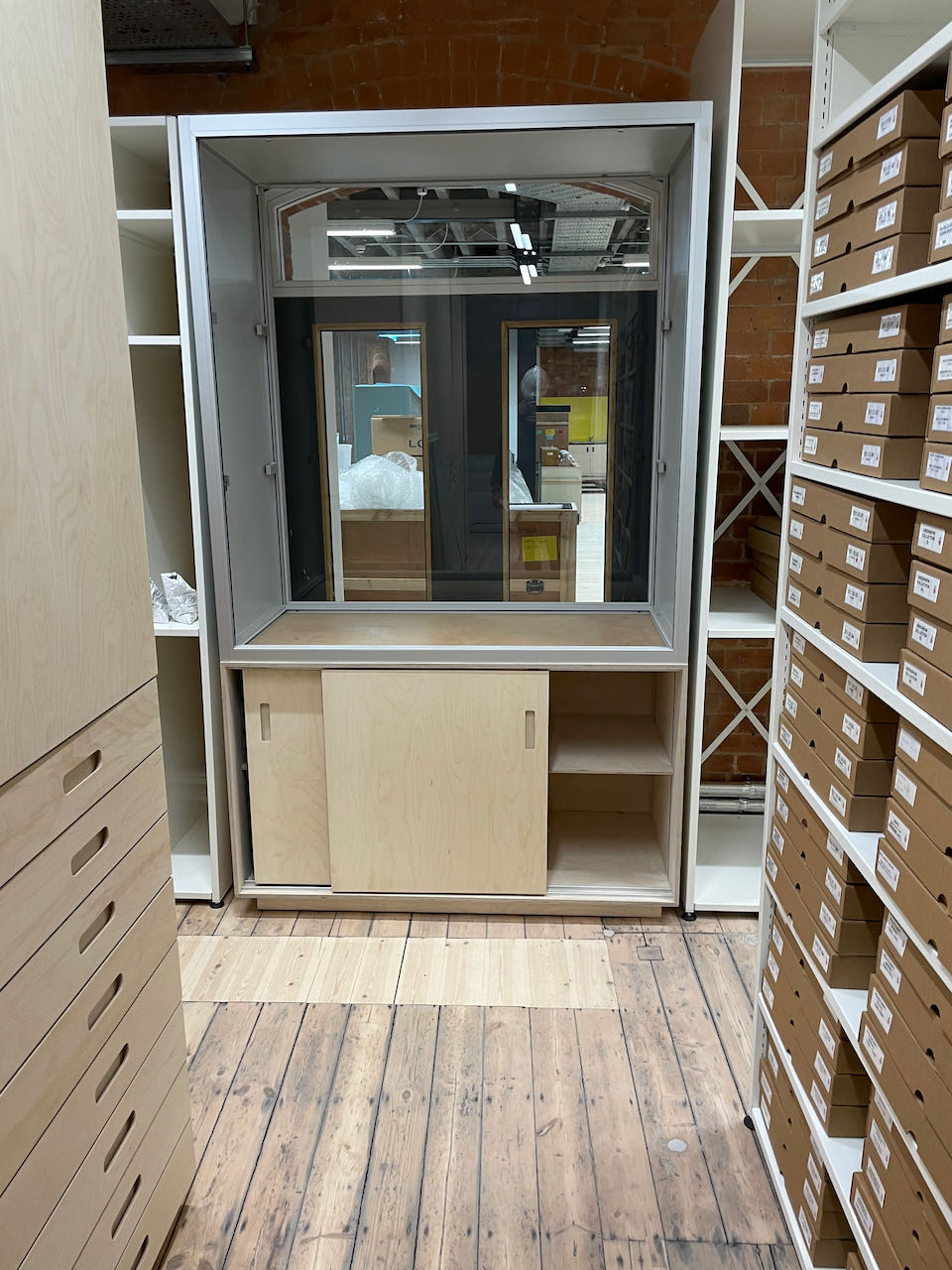 A row of cream coloured metal racking with dozens of tan boxes on them