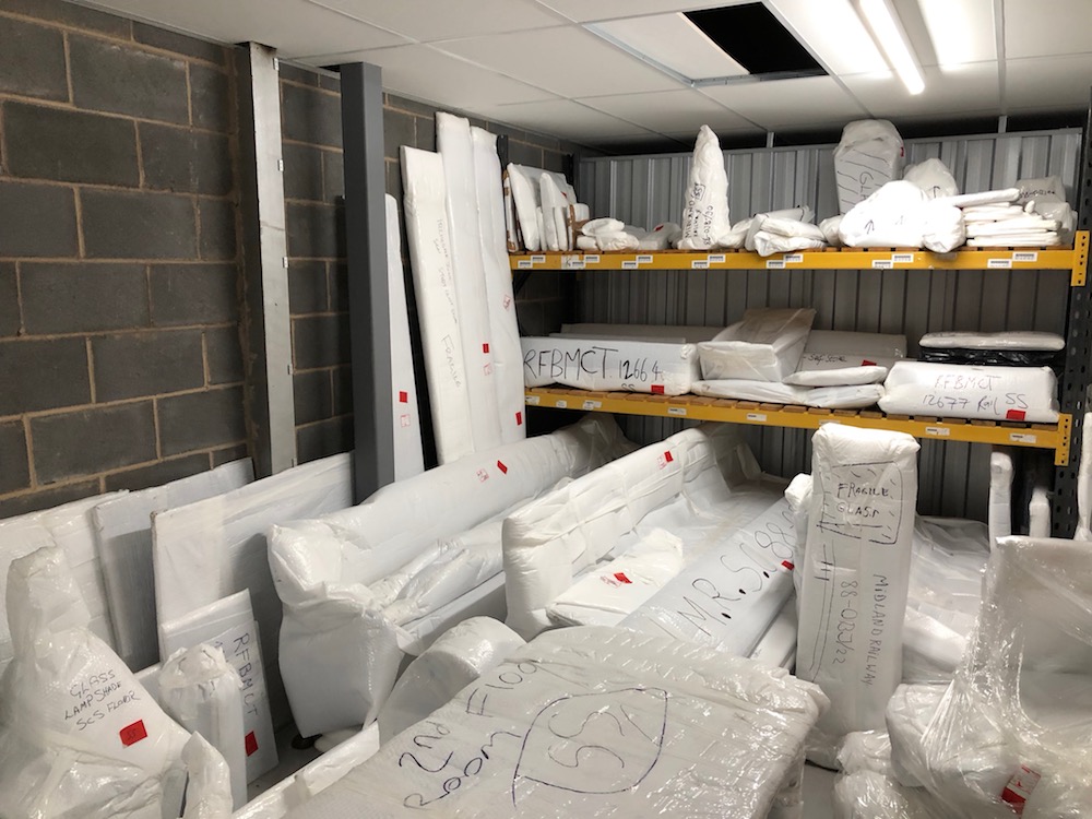 Many objects in a store room, all wrapped in protective white plastic