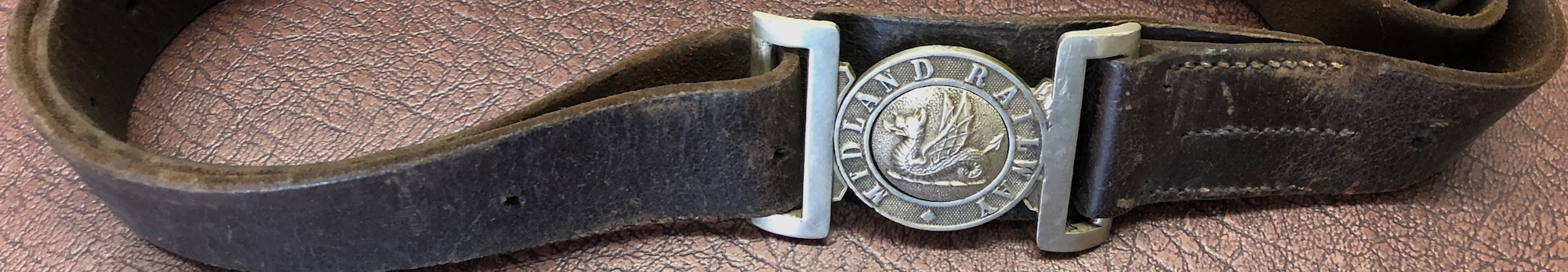 A break-section banner formed of a leather belt with the buckle reading MIDLAND RAILWAY - probably from a policeman's uniform.