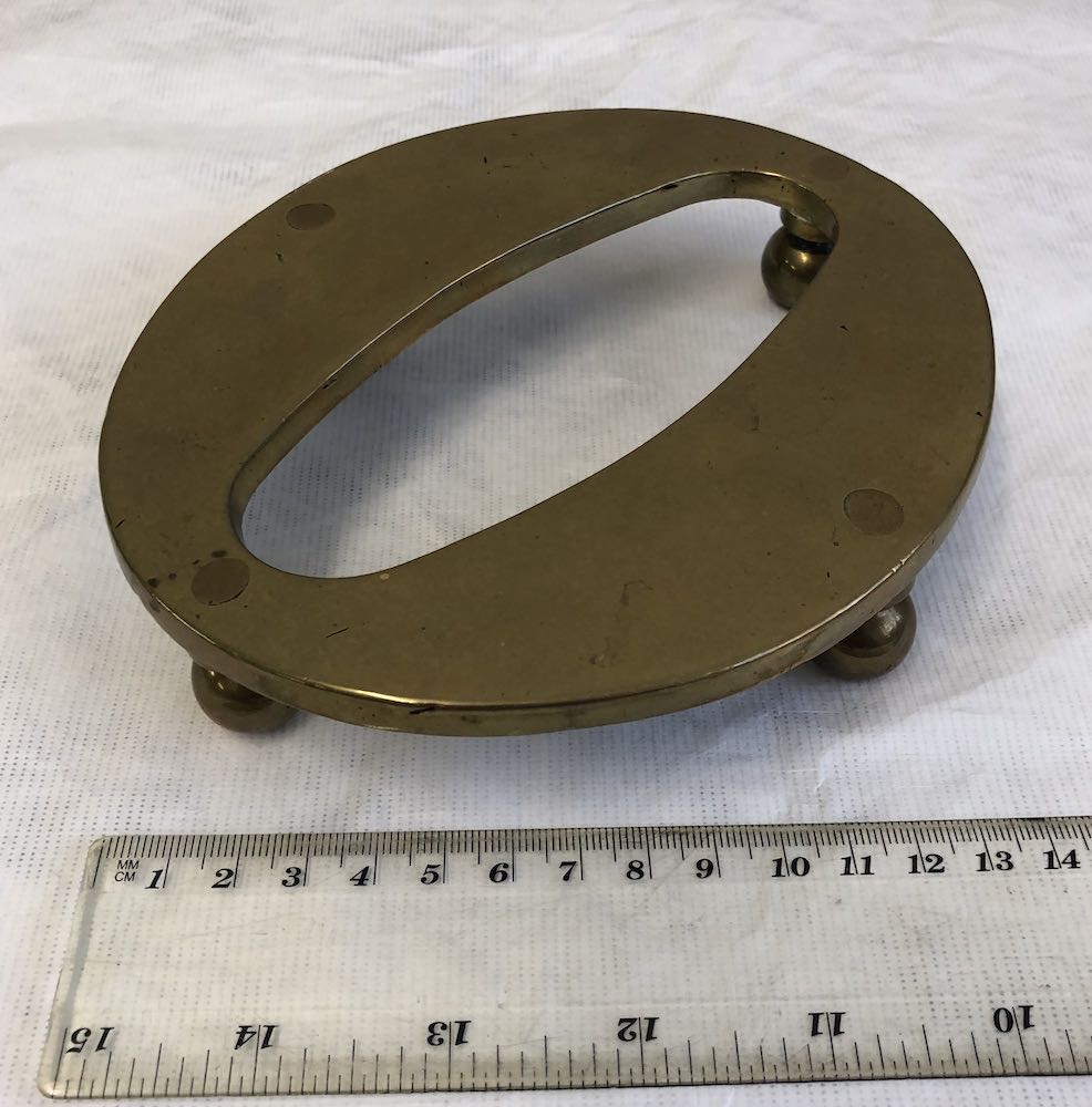 A brass figure zero with feet attached to it to make it a teapot stand