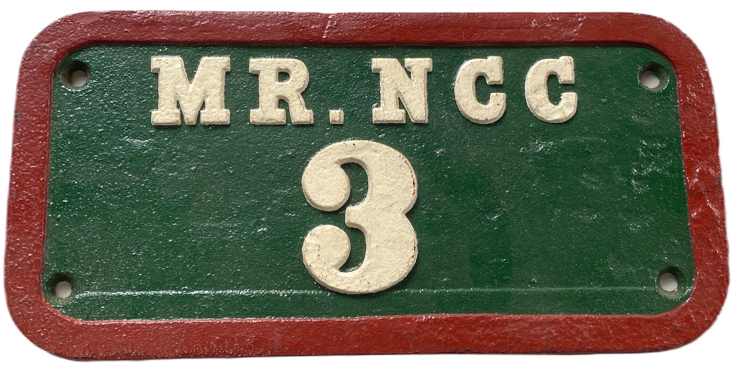 A rectangular cast iron plate with rounded corners bearing the lettering MR. NCC and the large figure 3. It is pained green with red edges and the writing is white, though this has the appearance of a relatively recent restoration.